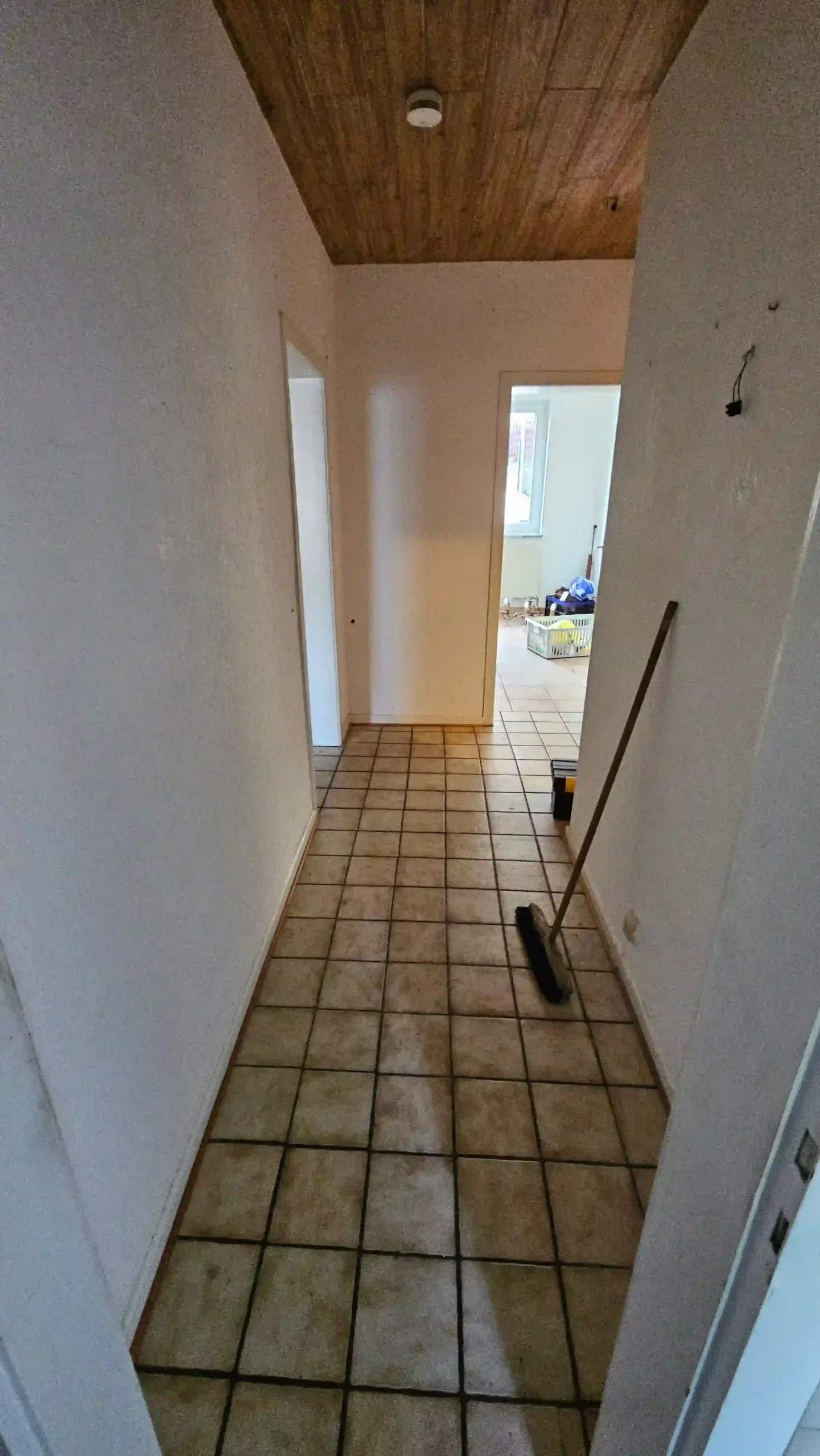 Haushaltsauflösung Gefliester Hausflur mit Holzdecke, Besen und offener Tür zu einem Nebenraum