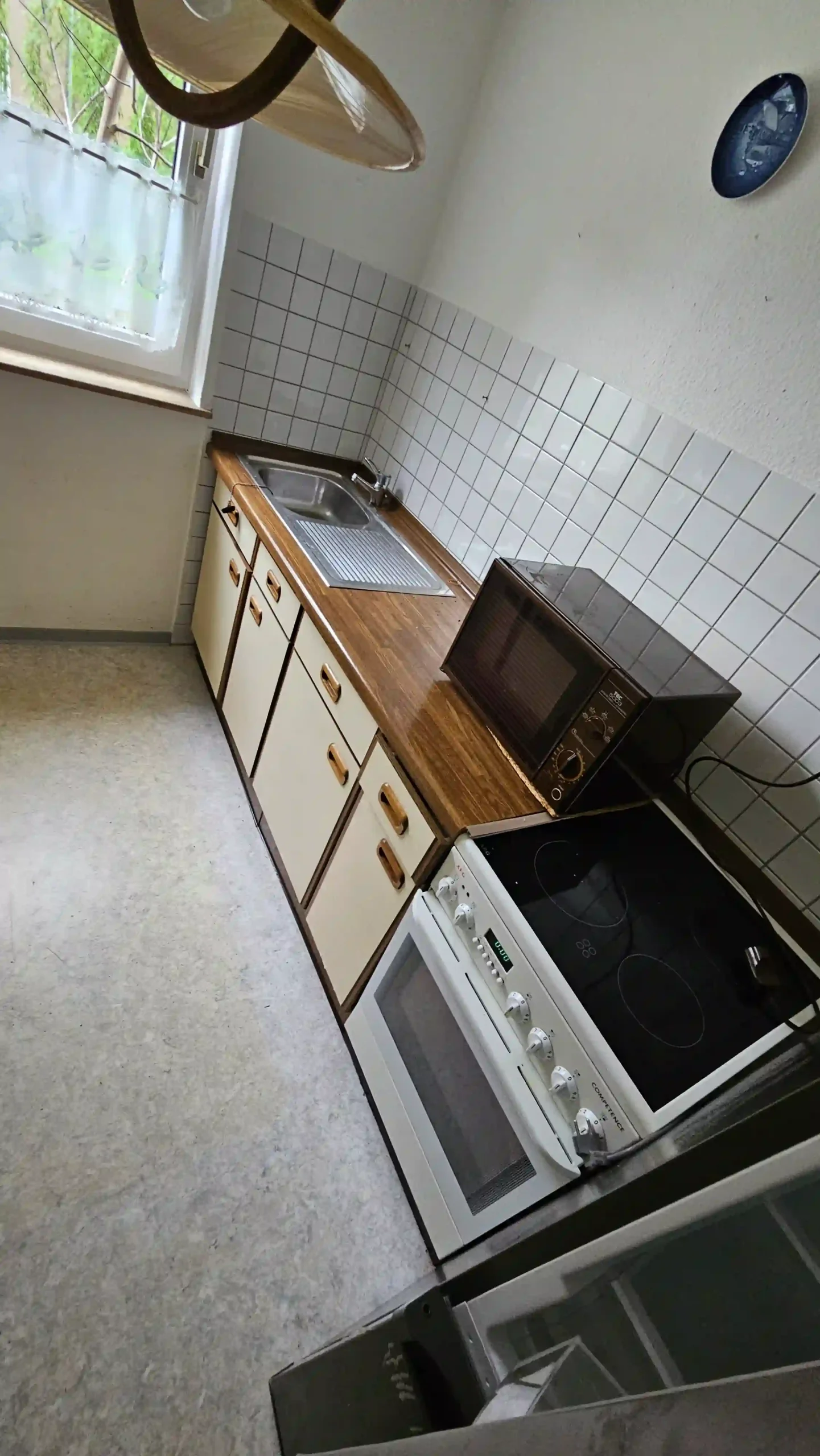 Haushaltsauflösung Küchenzeile mit Spüle, hellen Unterschränken, freistehendem Herd und kleinem Backofen